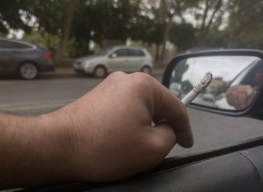 Sigara içen ve camları açık araba kullanan bir adam. Dikkati dağılmış sürüş kazaları kavramı