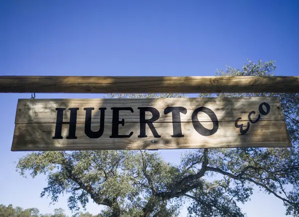 Organing kitchen garden hanging sign at mediterranean background. Spanish language letters