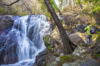 Gezgin adam kışın Nogaleas şelalesine fotoğraf çekiyor. Navaconcejo, Caceres, Extremadura, İspanya