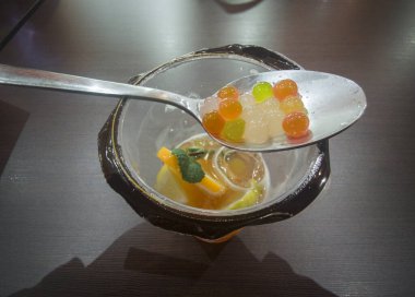 Bir kaşık dolusu çiğnenmiş küre bir fincan köpüklü çay. Ahşap masa yüzey arkaplanı