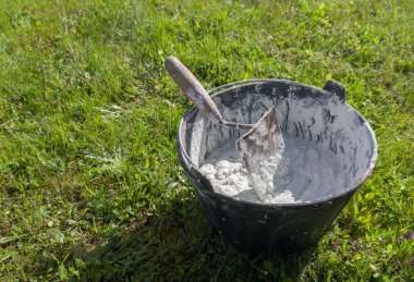 Kova dolusu beyaz yapışkan havan topu uygulamaya hazır. Arkaplan olarak yeşil çimen