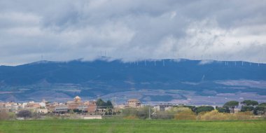 Wind turbines on the top of the hills. Little town in the foreground clipart