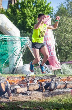 Merida, Spain - May 18th, 2024: FarinatoRace Merida 2024. Runner at finish line with a burning log clipart