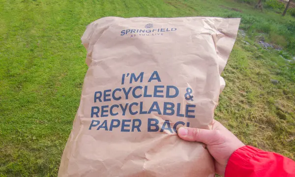 Stock image Merida, Spain - Feb 24th, 2024: Hand holds an Springfield Package made of recyclable paper and with the recyclable indication