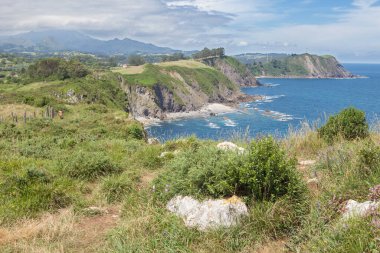 Kırmızılı kadın Cehennem Kayalıkları 'nın yanında yürüyor, Ribadesella Doğu Asturias, İspanya