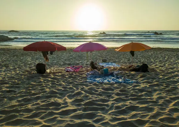 Stock image Three umbrellas placed on sand facing the sea. Nossa Senhora beach, Zambujeira do Mar, Portugal