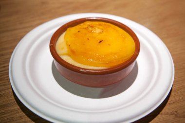 Ahşap arka planda kil bir kasede servis edilen katalan kremi. Seçici odak