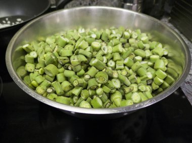 Dilimlenmiş fasulye kabukları pişmeye hazır. Alüminyum bir kaseye yerleştirilmiş.