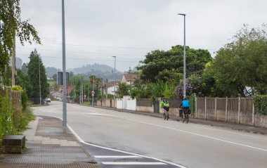 Kırsal bir kasabadan geçen MTB bisikletçileri. Gökyüzü bulutlu