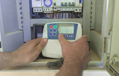 Bahçıvan otomatik sulama sistemi programlıyor. Aygıtın elektrik panelindeki manipülasyonu