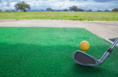 Golf yeni başlayanlar için golf sahası. Sarı top ve golf sopası ile golf hasırı