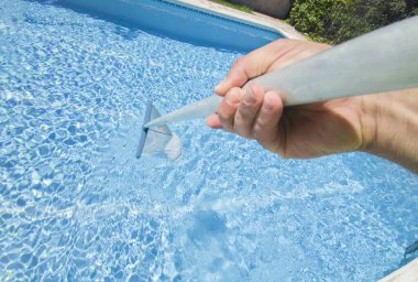 Havuzun yüzeyini kepçeyle temizleyen işçiler. Yüzeyde yüzen toprak ve enkaz biriktiriyorlar.