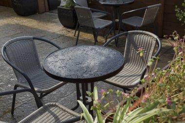 Yağmurdan sonra yuvarlak bir masaya düşer ve bahçede hasır sandalyeler