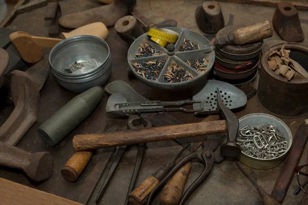 Tools for shoemaking, a hammer, shoes for tailoring, an awl, metal and wooden nails, a meter located on the desktop