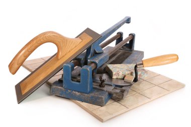 Beyaz arkaplandaki fayansları kesmek için kullanılan bir araçla spatula ve mala