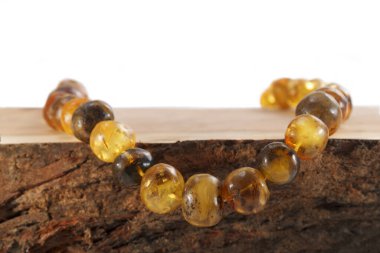 Tahta bir kesiğe yerleştirilmiş düzensiz şekilli gerçek doğal kehribardan kolye.