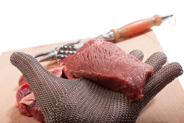A piece of meat on a hand with a chainmail glove