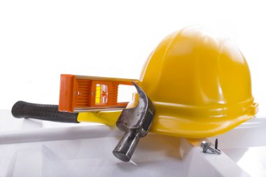 Sarı başlık, çekiç, kat ve vida beyaz arka planda çatıyı bağlamak için