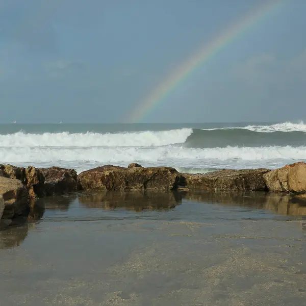 海の地平線にピアと虹が付いている海岸 ロイヤリティフリーのストック画像