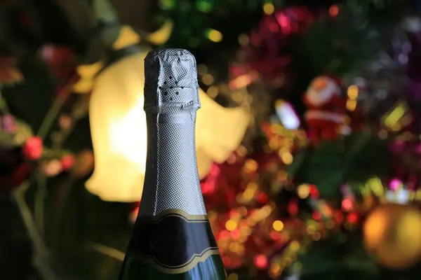 おもちゃやガーランドで輝くクリスマスツリーの背景に閉じたシャンパンのボトル ストックフォト