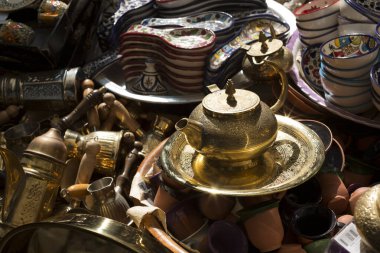 Bronz çaydanlıklar, tepsiler, seramik kaplar, finjanlar yüzeyde rastgele dağılmış.