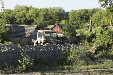 Ukrayna kırsal evi ve bahçede terk edilmiş traktör.