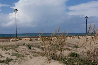 Deniz kıyısında, gökyüzünün arka planında yağmur bulutlarıyla yürüyorum.