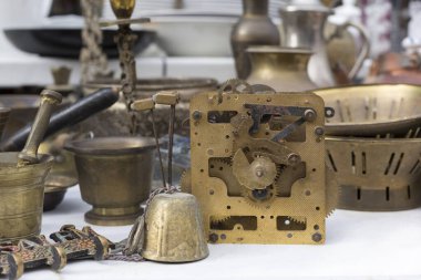 Parçalanmış mekanik saat mekanizmaları ve antika bronz kaplar pazarda satılıyor.