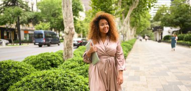 Çekici mutlu stil artı Afrikalı Amerikalı kadın öğrenci saçı dışarıda dizüstü bilgisayarı, yazın büyük şehir caddesi. Çeşitlilik. Uzaktan ofis işi, uzaktan eğitim