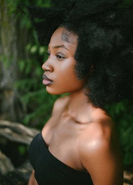 Kapalı moda portresi güzel Afro-Amerikan siyah kadın çıplak omuzlar, güneşli yaz günü yeşil yapraklar. Yüz bakımı. Kozmetoloji, mükemmel cilt bakımı ve kaplıca
