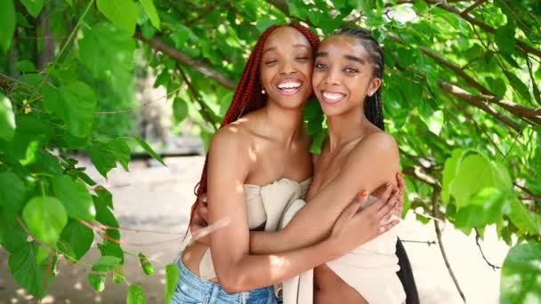 紧贴户外肖像画美丽的非洲裔美国女黑人夫妇 金发碧眼 洁白的牙齿完美地笑着 姐妹们在阳光灿烂的夏日拥抱在一起 护肤和温泉 — 图库视频影像