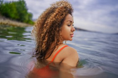 Çekici mutluluk artı boyut Afro-Amerikan siyahi kadın açık havada deniz gölü suyunda su sıçratarak yüzmeyi seviyor.