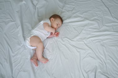 Yeni doğmuş şirin çocuk beyaz çarşafların üzerinde ya da beşiğinde huzur içinde uyuyor. Bebek eşyaları paketleme şablonu. Sağlıklı çocuk, hastane kavramı ve mutlu annelik. Bebek, bebek. Çocuk odası..