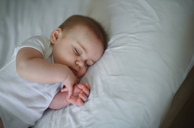 Yeni doğmuş şirin çocuk beyaz çarşafların üzerinde ya da beşiğinde huzur içinde uyuyor. Bebek eşyaları paketleme şablonu. Sağlıklı çocuk, hastane kavramı ve mutlu annelik. Bebek, bebek. Çocuk odası..