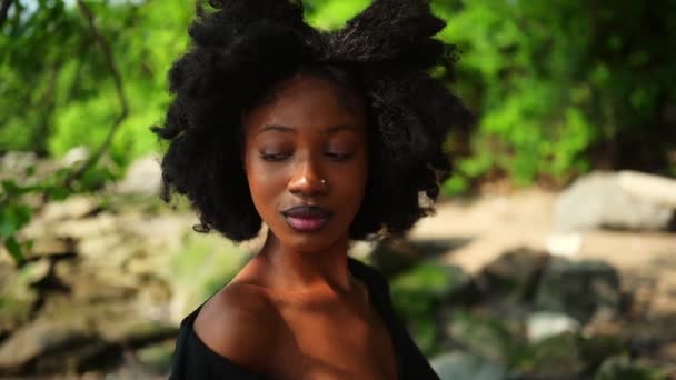 スローモーションの肖像画を閉じる美しい若いアフリカ系アメリカ人黒人女性完璧な白い歯は外で笑みを浮かべて 晴れた夏の日の緑の葉 顔の治療 スキンケア — ストック動画