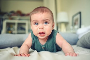 Çocuk odasında, mavi gözlü, keten elbiseli, bebek odasında ağlayan sevimli sarışın bir çocuğun portresini yakından çek. Çocukça öfke nöbeti. Bebeği yatırmakta zorlanıyorum.