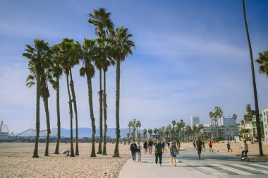 10 Mart 2024, Los Angeles, ABD. Venedik plajı güneşli bir günde. Yaya geçidi boyunca yürüyen turist kalabalığı var. Bisikletçiler bisiklet yolunda gezerler. Güzel okyanus manzarası
