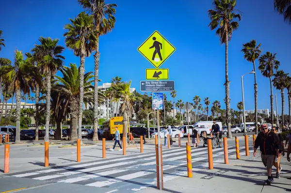 10 Mart 2024, Los Angeles, ABD. Venedik plajı güneşli bir günde. Yaya geçidi boyunca yürüyen turist kalabalığı var. Bisikletçiler bisiklet yolunda gezerler. Güzel okyanus manzarası