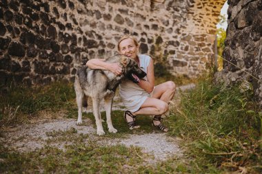 Mutlu gülümseyen yaşlı olgun kadın turist Avrupa 'nın antik kalesinde evsiz büyük köpeğe sarılıyor. Emekli sportif aktif yaşlı insanlar ve evcil hayvanlar konsepti