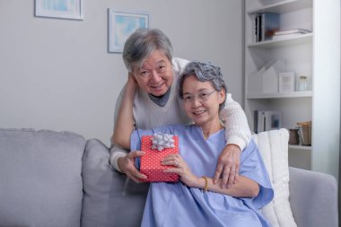 Kameraya bakan yaşlı bir çiftin portresi. Asyalı son sınıf öğrencisi koca, Sevgililer Günü 'nde sürpriz hediye kutusunu evde kanepede oturmuş, olgun kadının hediyesini alırken gülümsüyor. Mutlu yıllar.