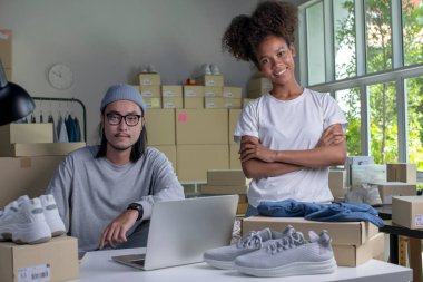 Confident mixed race young couple of Asian man and african-american woman retail seller, entrepreneur, online store drop shipping small business owner looking at camera in delivery shipping warehouse