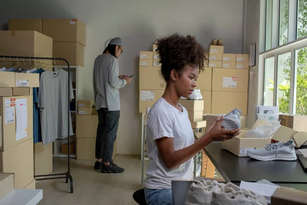 Mixed race couple of Asian man and African-American woman online seller e-commerce business owner working together in store warehouse.