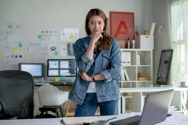 Portrait of Asian female graphic designer looking at camera in office.