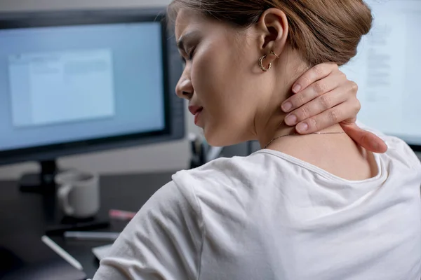 Tired woman massaging rubbing stiff sore neck tensed muscles fatigued from computer work in incorrect posture feeling hurt joint shoulder back pain ache.