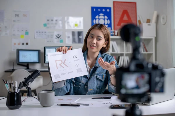 Young Asian female graphic designer blogger influencer talking looking at camera shooting education tutorial vlog training filming video course for social media at studio.