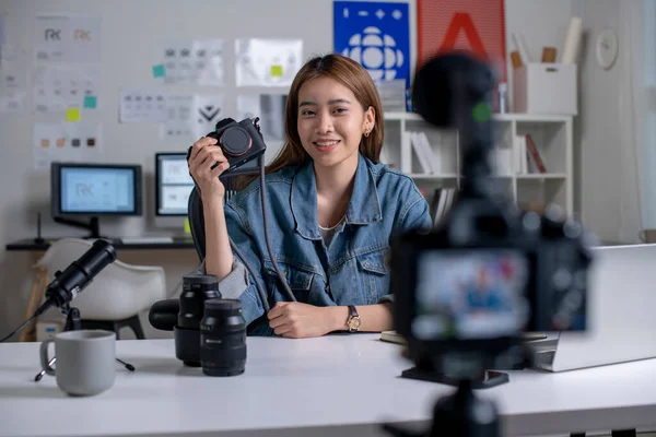 Young Asian woman designer,photographer blogger influencer filming teaching camera tutorial while looking at camera shooting education tutorial vlog training filming video course for social media at studio.