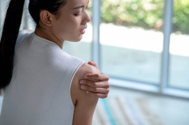 Asyalı kadının omuz ağrısı var. Başka bir elle acı çeken omuz tutan bir kadın. Vücut-kas problemi, sağlık ve ilaç sorunları olan insanlar..