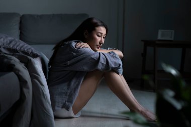 Yatak odasındaki genç Asyalı kadın üzgün, yorgun ve endişeli zihinsel sağlıkta depresyon yaşıyor.