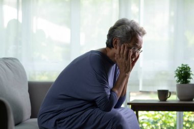 Oturma odasında üzgün ve yalnız Asyalı bir kadının portresi.