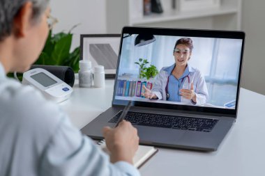 Asian woman with laptop during an online consultation with her doctor in her living room, telemedicine concept clipart